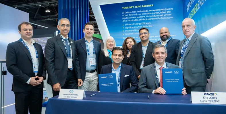 Group of people around a table with two people sitting with signed documents