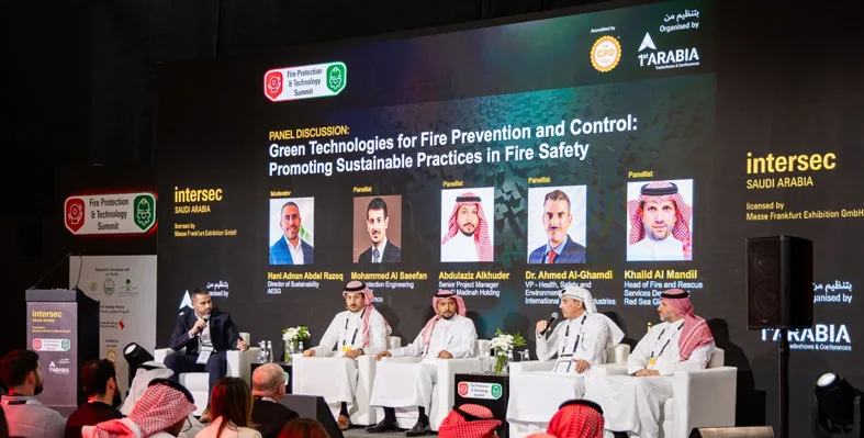 A panel discussion featuring several speakers in traditional Saudi attire.