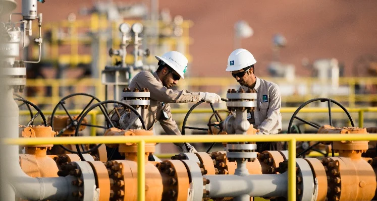 Aramco employees in white hard hats with valves and pipes