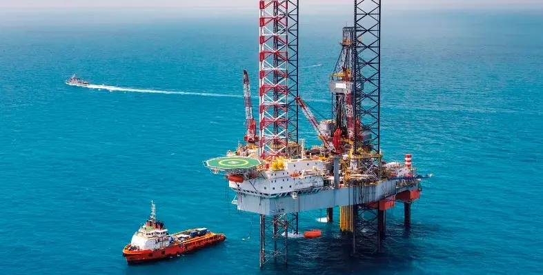 A boat sailing past an offshore oil rig.