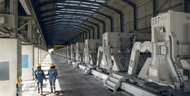 Two workers in PPE walking through an Emirates Global Aluminium (EGA) facility.