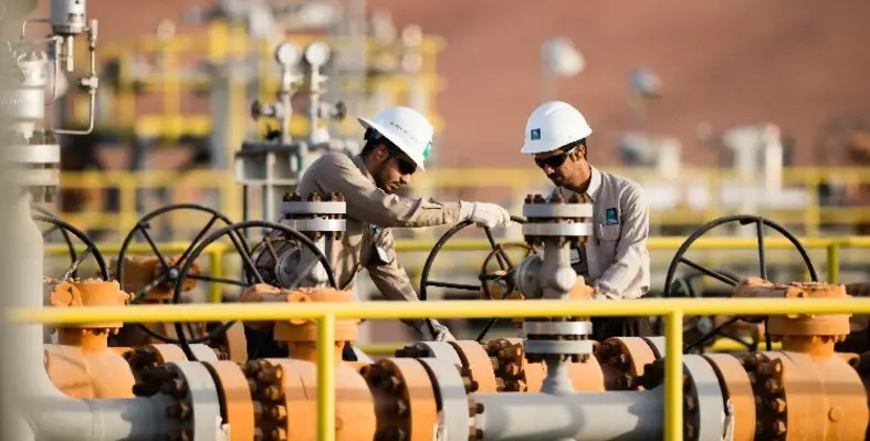 Aramco employees in white hard hats with valves and pipes